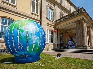 Aufblasbare Erdkugel auf einer Wiese vor einem Gebäude.