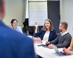 Foto: Personen sitzen in einem Hörsaal und hören einem Vortrag zu.