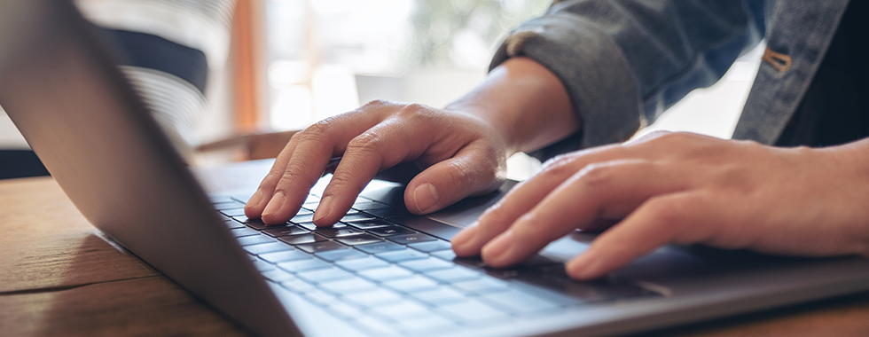 Nahaufnahme von Frauenhänden, die auf der Tastatur eines Laptops liegen