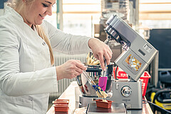 Doctoral candidate Natalie Feller portions the bread dough with alternative proteins instead of gluten into the mini loaf pans for the baking line 30g at a time. | Image source: University of Hohenheim / Oliver Reuther