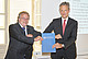 Markwart von Pentz (r.), Präsident der Landtechniksparte im US-amerikanischen Unternehmen Deere & Company, erhält von der Fakultät Agrarwissenschaften der Universität Hohenheim die Ehrendoktorwürde. Dekan Prof. Dr. Ralf Vögele überreicht die Urkunde mit einem Corona-Gruß. | Bildquelle: Universität Hohenheim / Jan Winkler